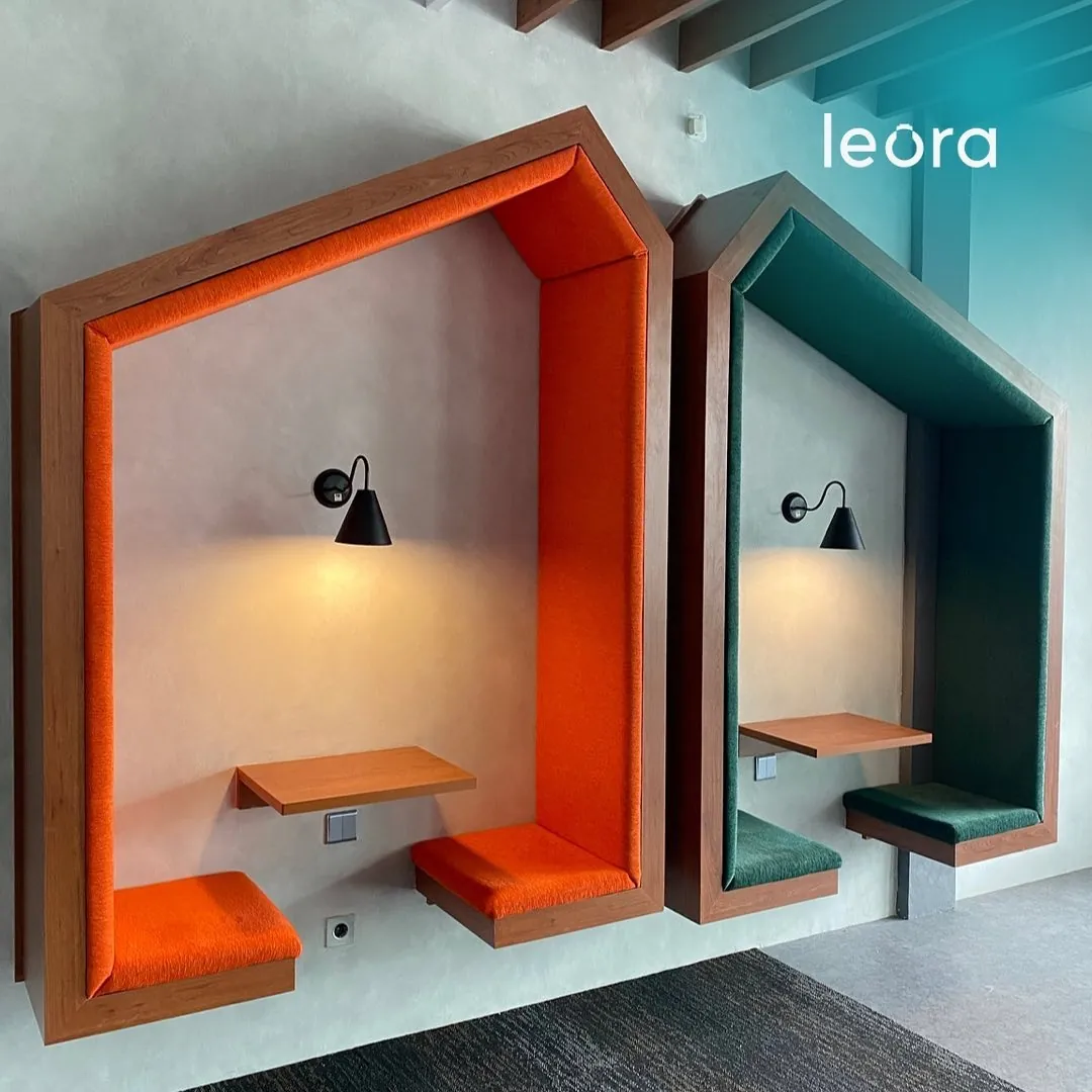 Two upholstered focus booths in orange and green built into a concrete wall