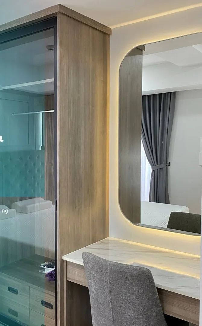 Sliding glass wardrobe beside a dressing table with a lit mirror